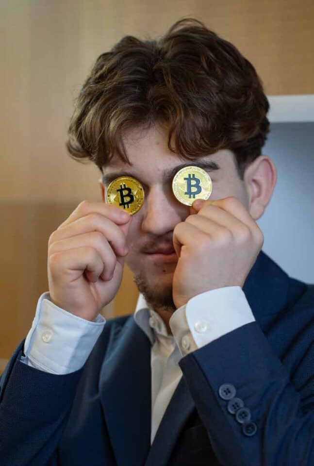 Mann hält Bitcoin-Münzen vor den Augen
